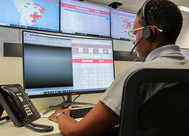 Um atendente da TeleHelp na frente do computador, usando um headset e de costas.